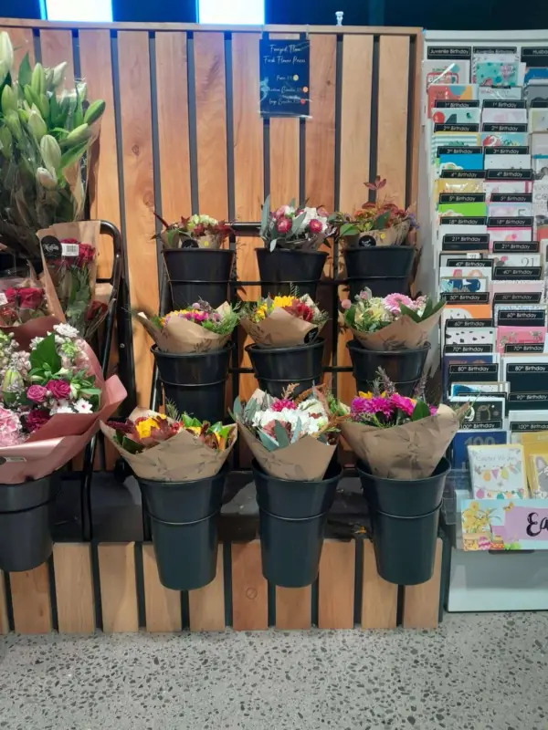 Foraged Flora posies on a wooden retail stand beside greeting cards