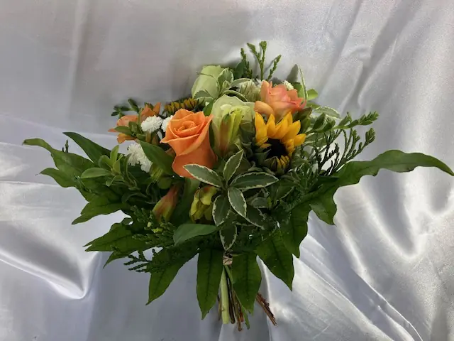 Hand-tied bunch of orange roses, sunflower and greenery