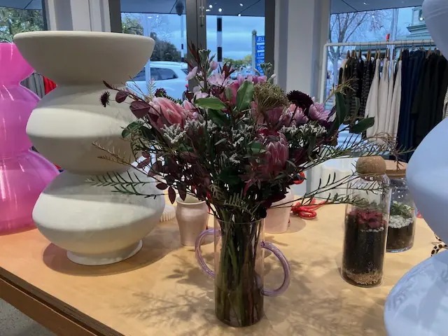 Pink protea arrangement in a glass vase on a shop counter