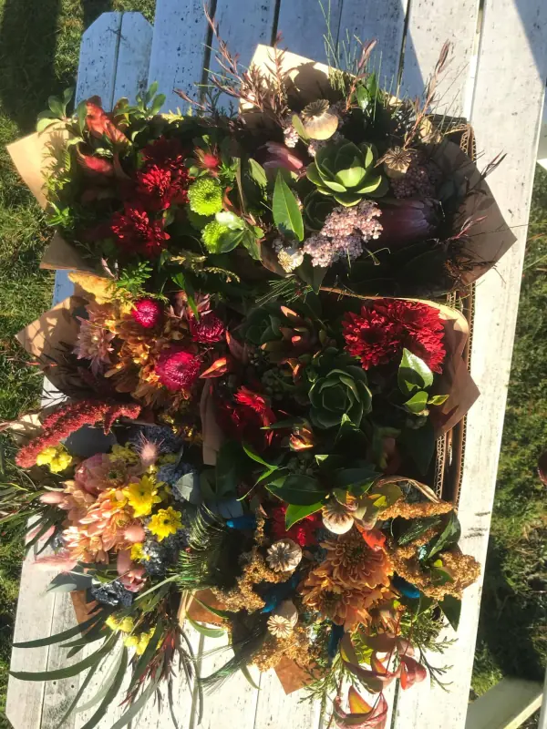 Assorted kraft-wrapped bunches with succulents, dahlias and dried flowers on a picnic table